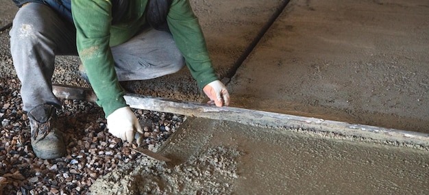 Construction worker aligns concrete screed floor