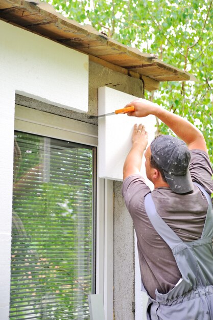 Construction worker applying insulation over exterior wall of house