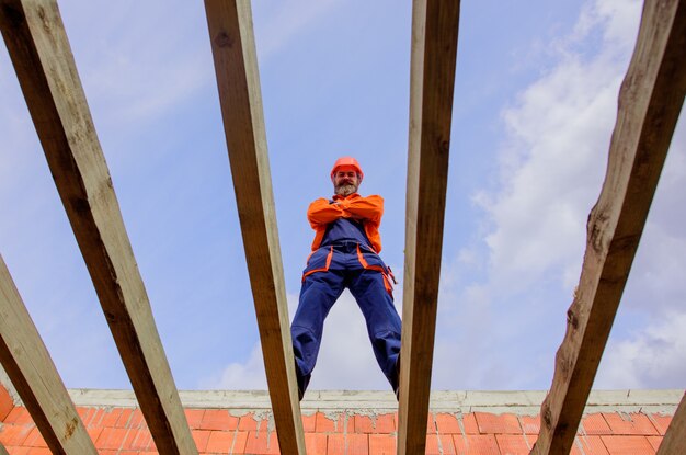 上の屋根構造に取り組んでいる建設現場の屋根葺き職人大工ビルダーの建設労働者