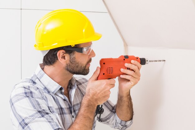 Construction worker drilling hole in wall