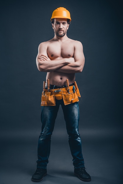 Construction worker. Full Length of young confident man keeping arms crossed and looking at camera while standing 