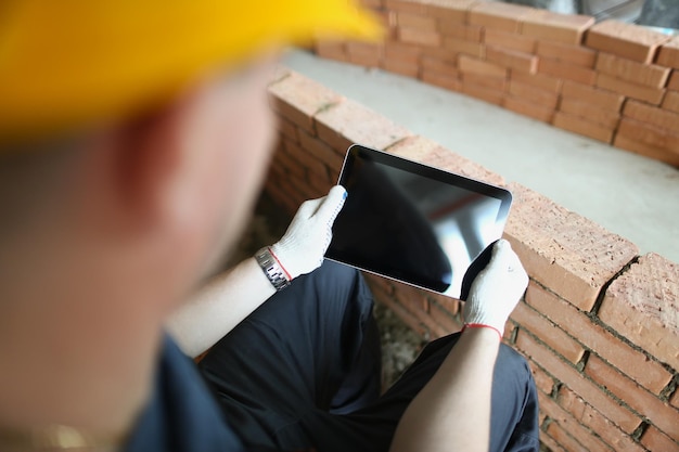 Construction worker holding tablet with black turned off\
screen