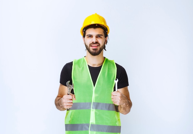 Construction worker holding wrench and spanner for mechanical repair.