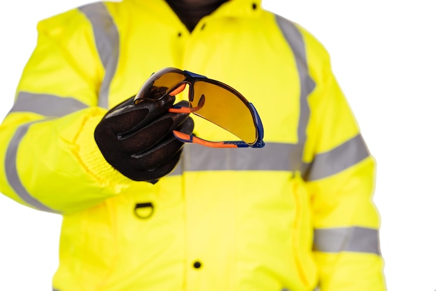 사진 hiviz 코트를 입은 건설 노동자가 시청자에게 어두운 색의 보안경을 제공합니다.