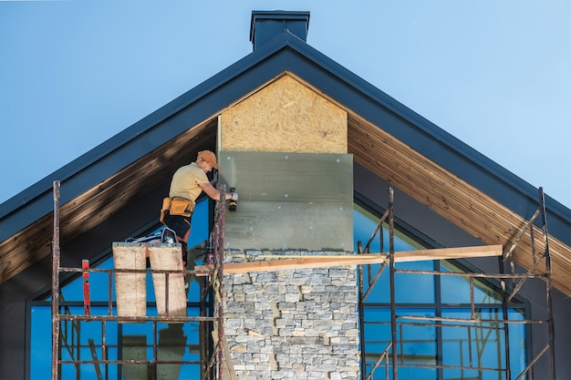 construction worker installing stone veneer on a modern home