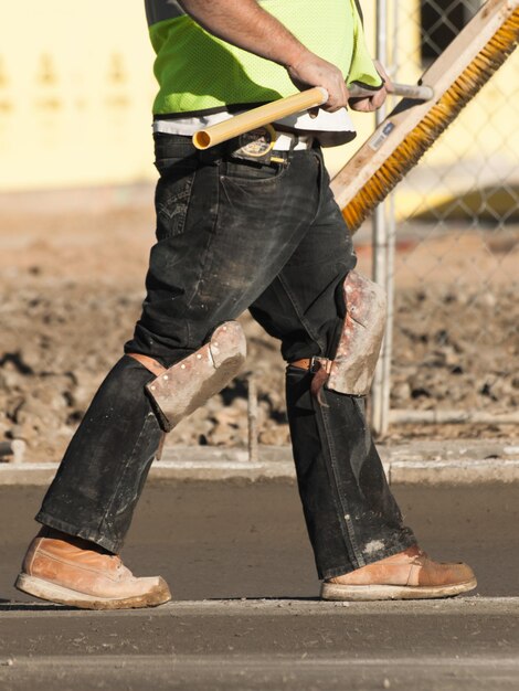 Construction worker leveling a new cement road.