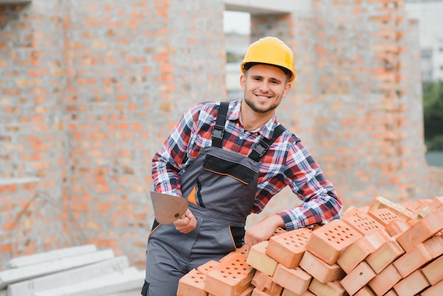 Construction worker man in work clothes and a construction helmet Portrait of positive male builder in hardhat working at construction site