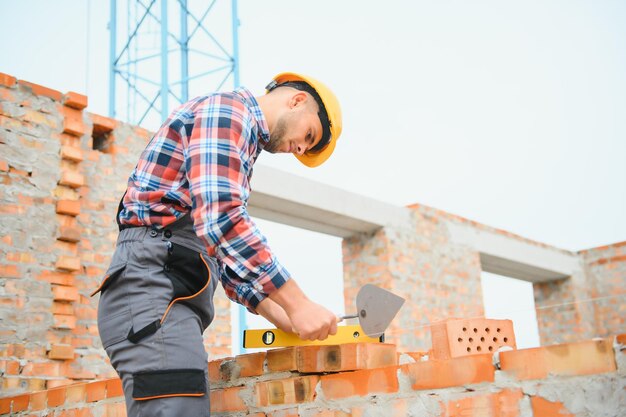 Construction worker man in work clothes and a construction\
helmet portrait of positive male builder in hardhat working at\
construction site