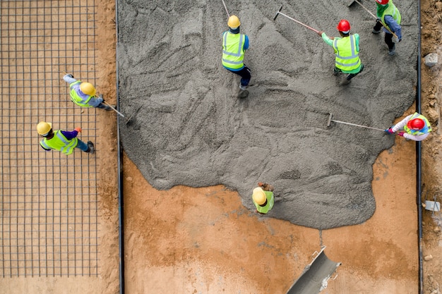 Строительный рабочий заливает мокрый бетон на дорожно-строительной площадке