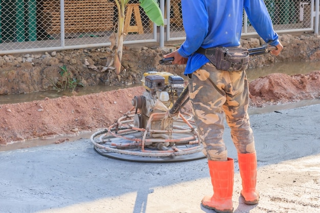 建設作業員がグラウトを生産し、特殊工具を使って湿ったコンクリートを仕上げる