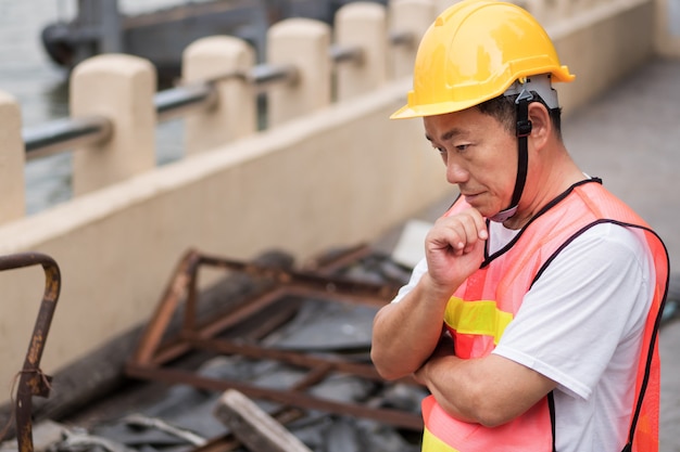 Construction worker thinking planning with pile of raw material