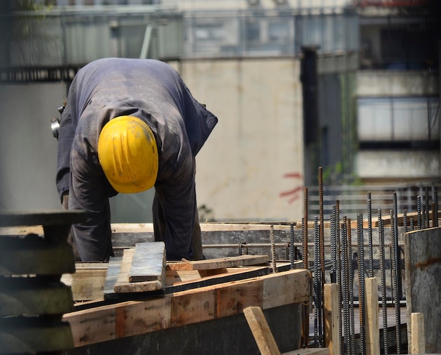 Foto operaio edile in cima a un edificio che indossa abiti da lavoro