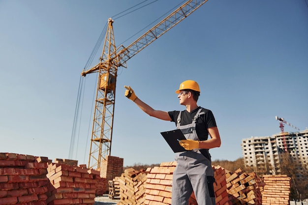 Operaio edile in uniforme e equipaggiamento di sicurezza ha un lavoro sulla costruzione