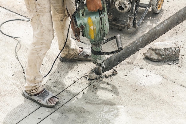 Construction worker using jackhammer drilling concrete surface