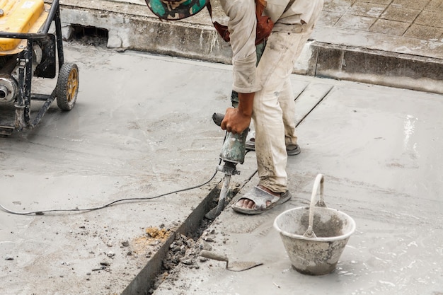 Foto operaio edile utilizzando martello pneumatico perforazione superficie di calcestruzzo