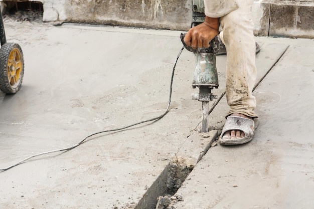 Construction worker using jackhammer drilling concrete\
surface