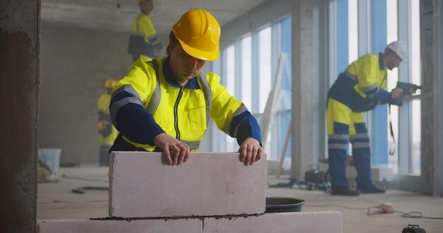 Photo construction worker using trowel and tools for building wall with bricks and mortar