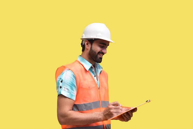 Construction worker wearing reflective vest and writing on\
clipboard indian pakistani model