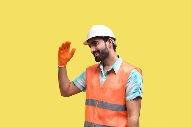 construction worker wearing safety gloves and posing over yellow background indian pakistani model