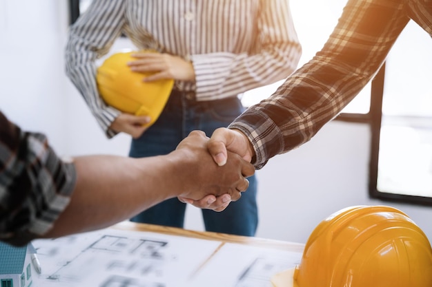 Photo construction workers architects and engineers shake hands while working for teamwork and cooperation after completing an agreement in an office facility successful cooperation concept