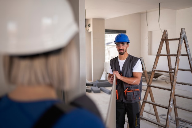 Lavoratori edili che trasportano insieme un cartello pesante