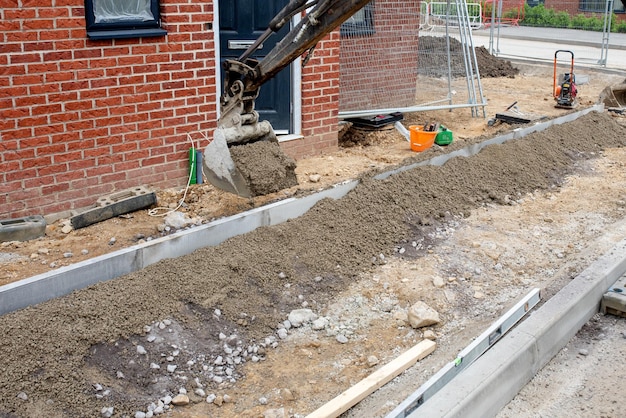 Construction workers finishing construction of new residential house and installing footpath