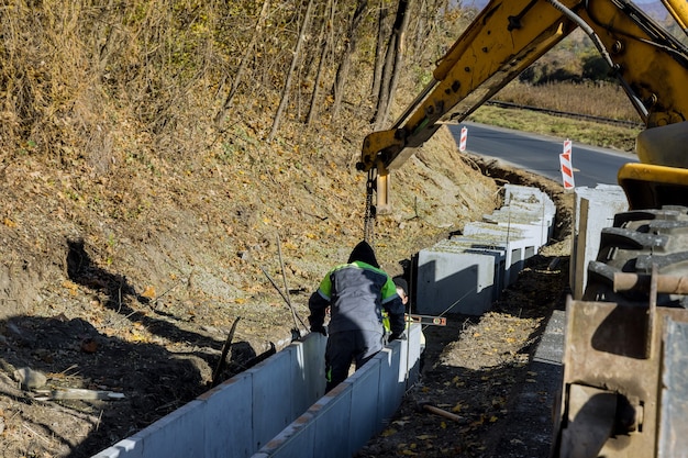 写真 建設作業員が再建道路にプレキャストu字型コンクリート排水路を設置