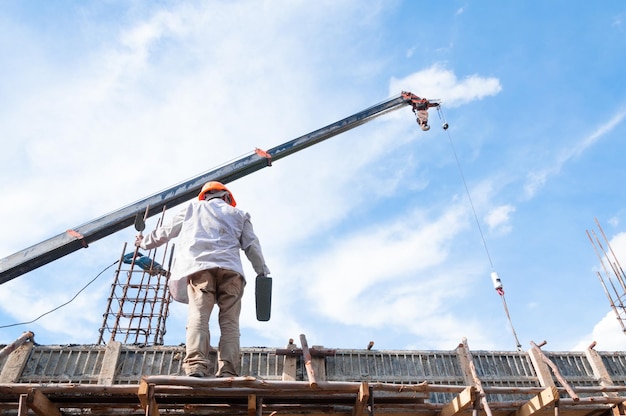 しっくいとspatulaManで足場に取り組んでいる建設労働者建設現場で青い空と高さでの作業に取り組んでいます