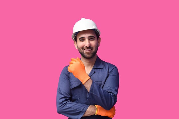 constructon worker wearing blue shirt smiling and posing over pink background indian pakistani model