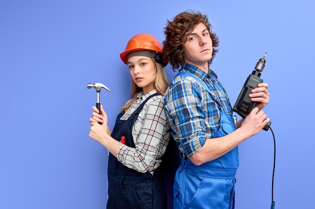 Constructors builders stand back to back to each other holding household tools