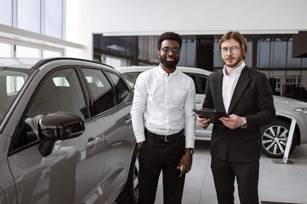 コンサルタントはクリップボードを使用して男性クライアントに新しい車に関するすべての情報を提供します