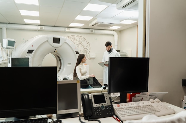 Consultation before computed tomography xray scan procedure to obtain detailed internal images of girls body Doctor with woman patient in CT scanning room in medical clinic