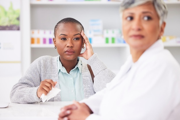 Photo consultation pharmacy and a black woman with a headache and a doctor for healthcare advice support pharmacist and an african patient at a clinic with a migraine and medical worker for help