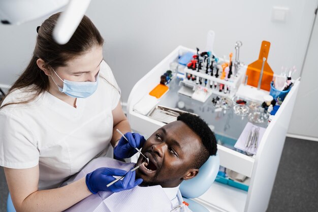 consultation with dentist at dentistry teeth treatment dentist examines african man mouth and teeth and treats toothaches african man patient of dentistry