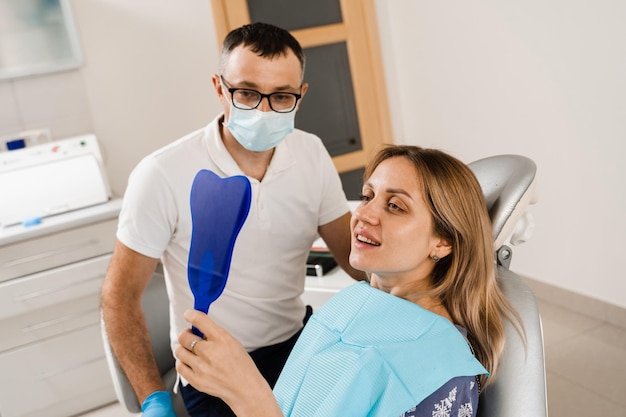 Consultation with dentist at dentistry Teeth treatment Woman looking in the mirror at the dentist Happy girl patient of dentistry