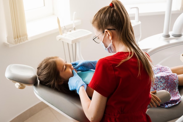 Consultation with pediatric dentist in dentistry Pediatric dentist examines teeth of child girl for treatment of toothache Pain in teeth in children