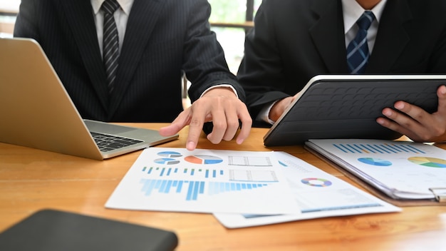Consulting business met two-man analyse financieren data met apparaat en papieren document.