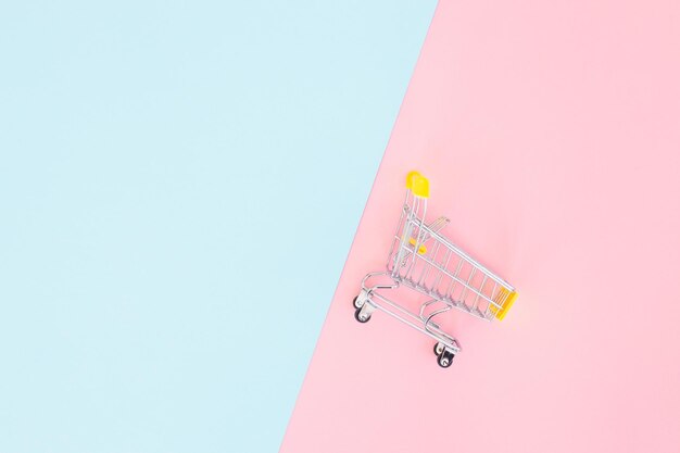 Consumer concept mini shopping trolley for shopping on a colored background minimalism top view