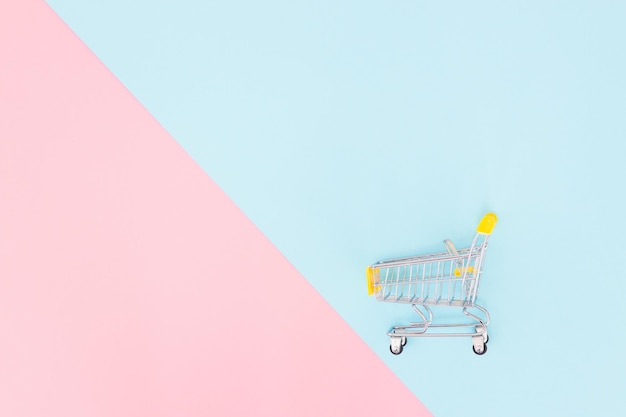 Consumer concept mini shopping trolley for shopping on a colored background minimalism top view