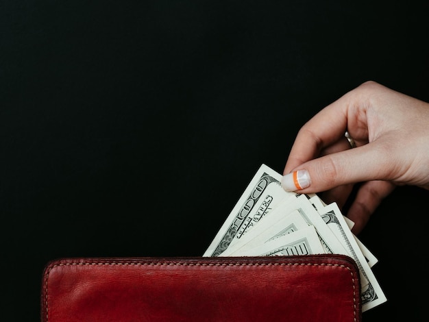 Consumerism and money spending or wasting personal finances and expenses woman taking out dollar banknotes from wallet