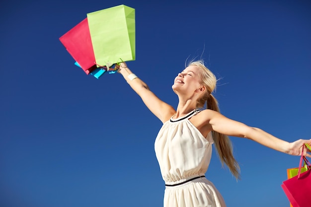 consumerism, sale and people concept - smiling woman with shopping bag rising hands