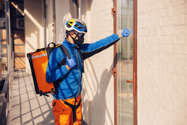 Contacless delivery service during quarantine. Man delivers food and shopping bags during isolation