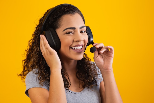 Contact the call center service. Customer support, female sales agent. Caller or operator of telephone operator or business woman in headset. Afro young woman. Zoom conference. yellow  background