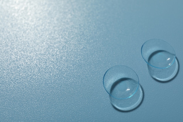 Contact lenses on blue background, space for text