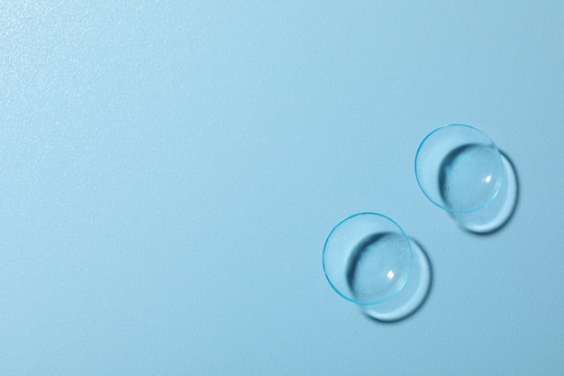 Contact lenses on blue surface, space for text