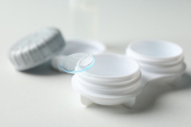 Contact lenses and case on white surface, close up