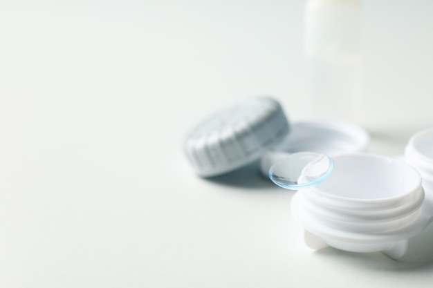 Contact lenses and case on white surface, close up