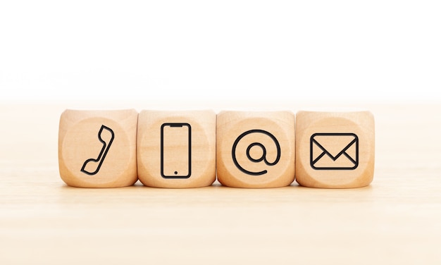 Contact us icons in wooden blocks on wooden desk. Copy space. 