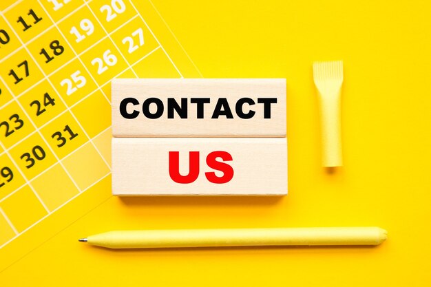 CONTACT US inscription on CUBES , Abstract calendar, yellow pen on a yellow background