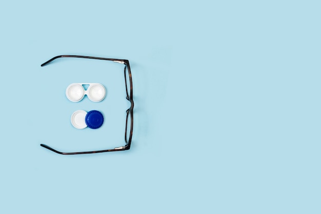 Contactlenskoker en bril op een blauwe achtergrond in een bovenaanzicht